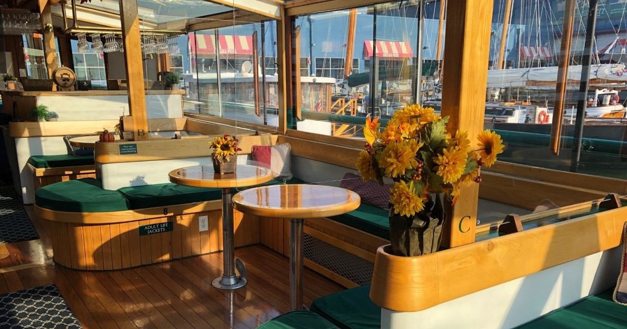 Cozy boat interior with sunflowers on tables and marina view.