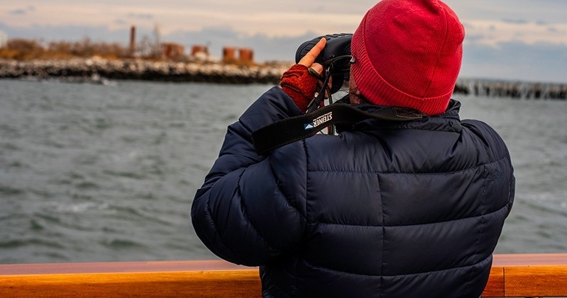 Person in red beanie taking photo over water from a boat.