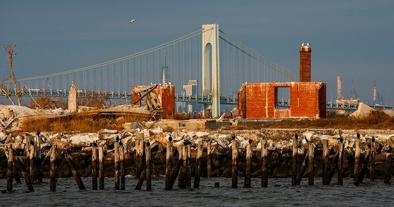 Old brick ruins with bridge in background, sea in foreground.