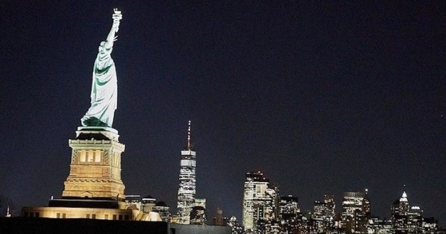 Statue of Liberty at night with the New York City skyline.
