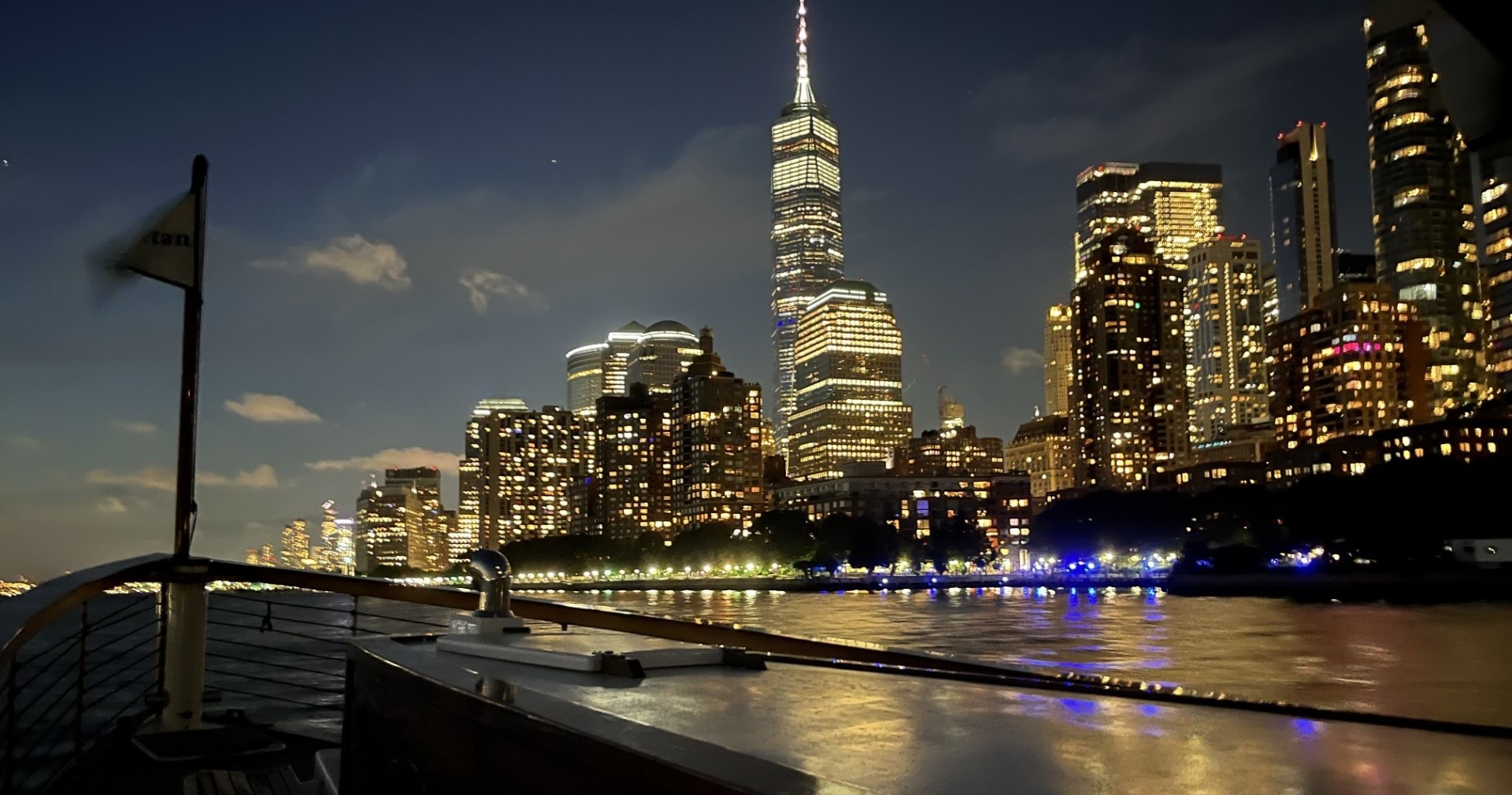 City skyline at night with illuminated skyscrapers and river.