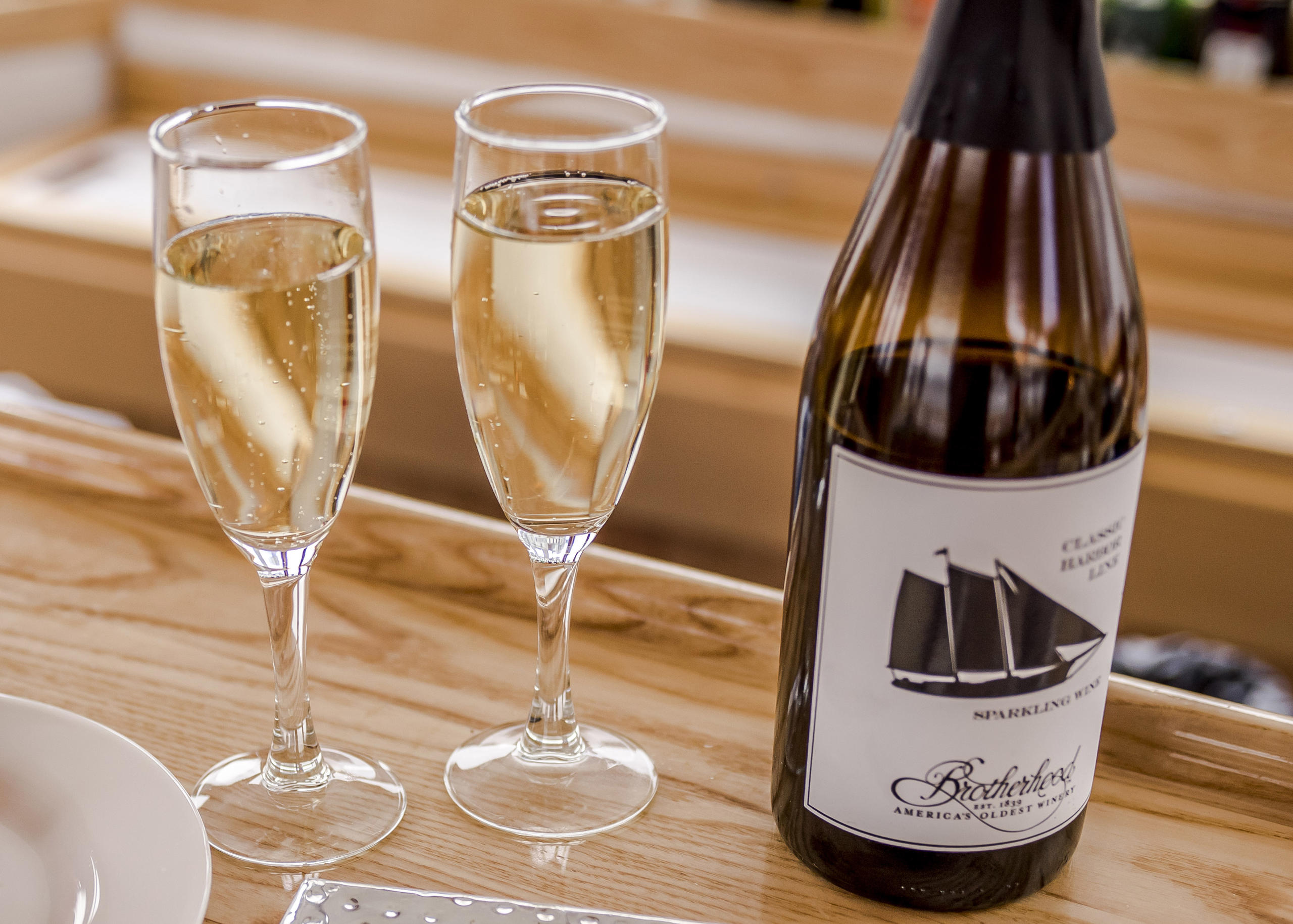 Two champagne flutes and a bottle on a wooden table.