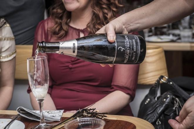 Person pouring champagne into a glass at a social gathering.