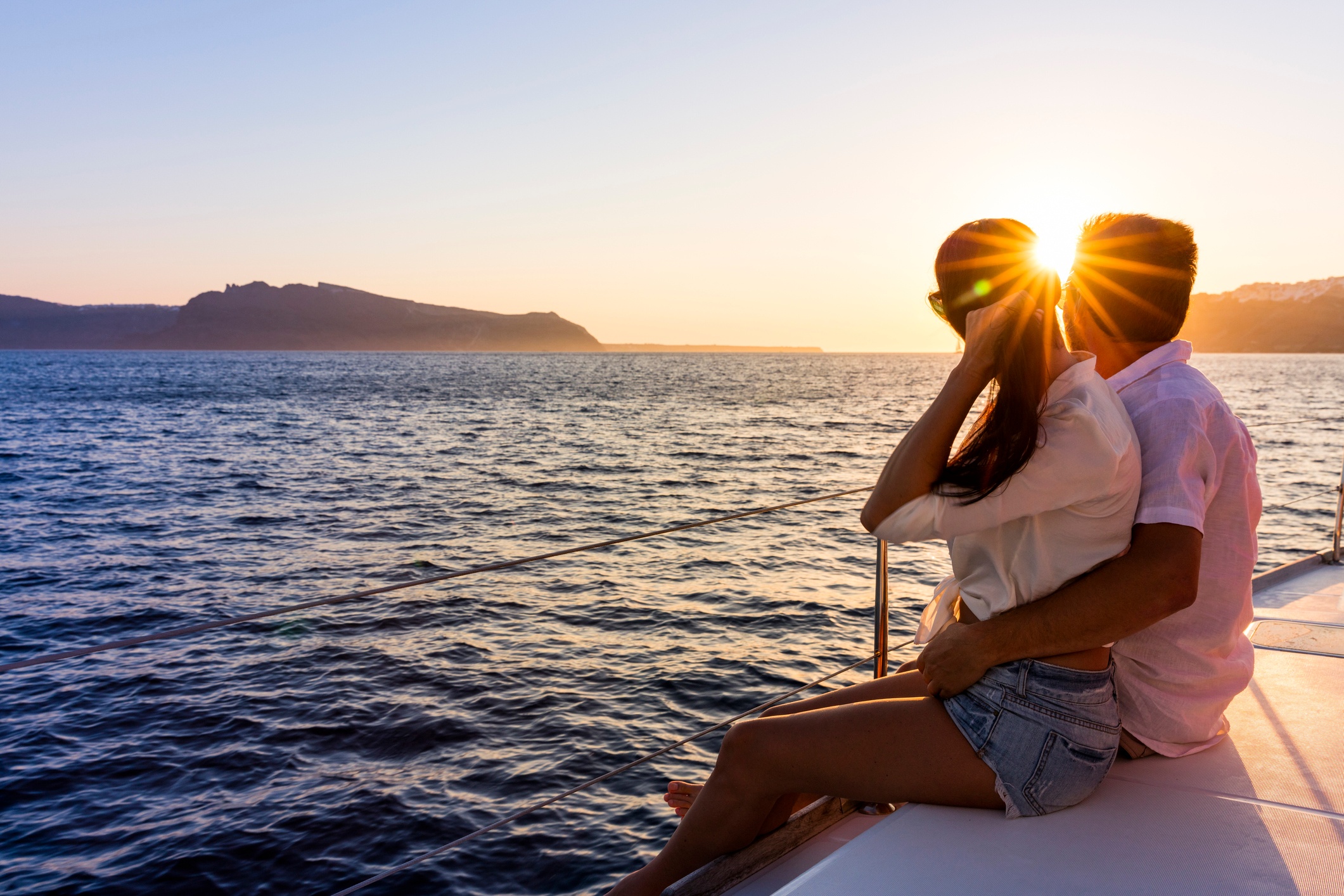 Couple sitting on a boat at sunset, overlooking the ocean.