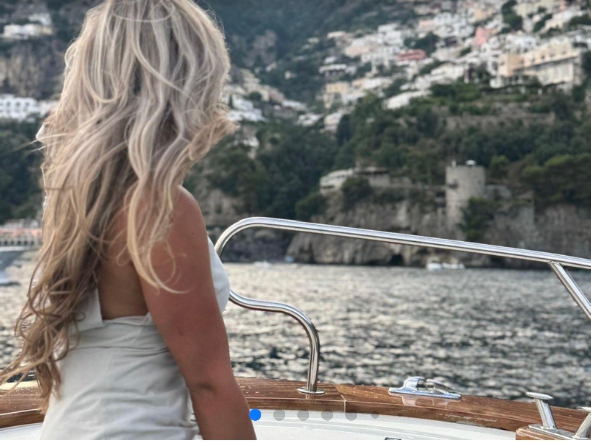 Person with long hair on boat, scenic coastline view
