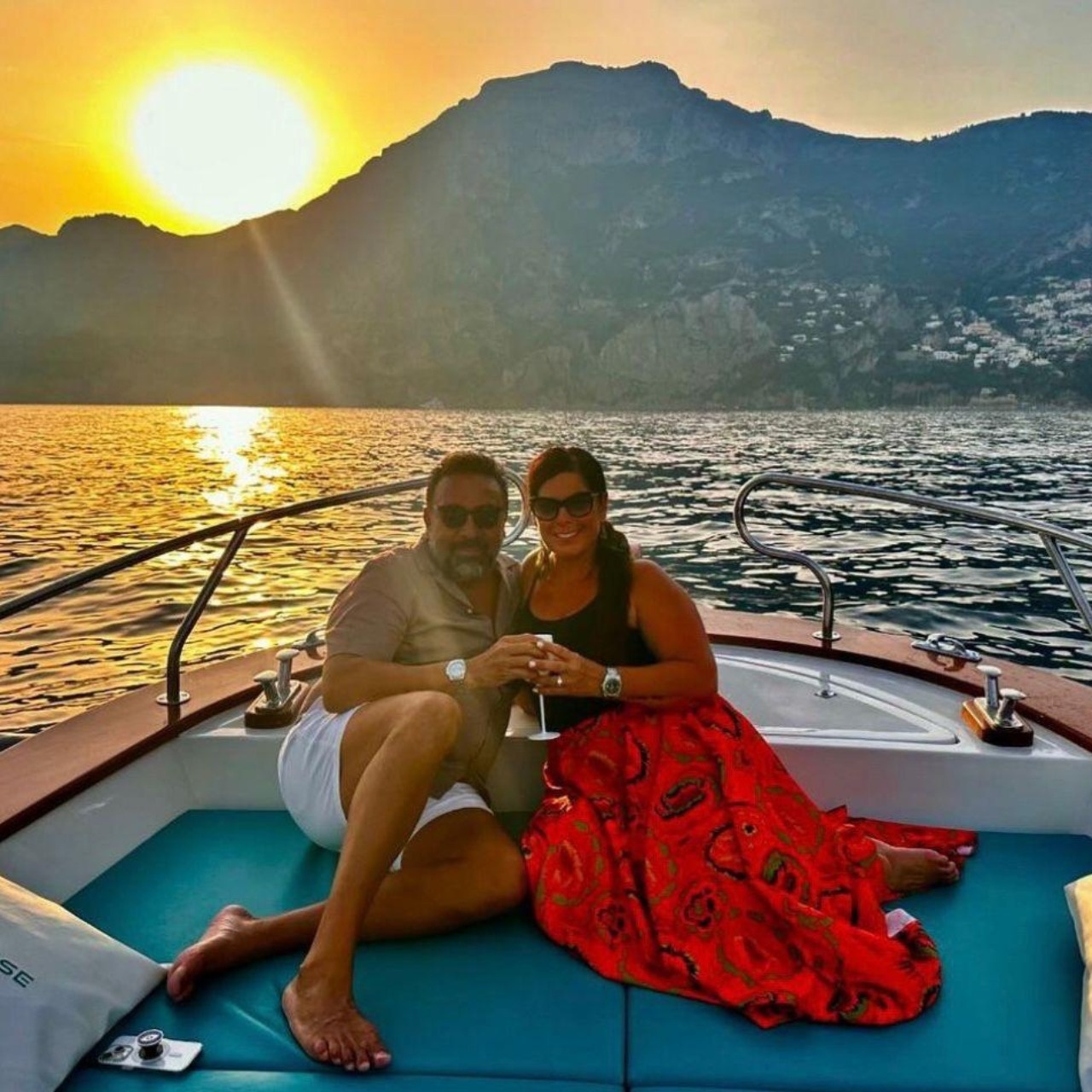 Couple on boat with sunset over mountain background.