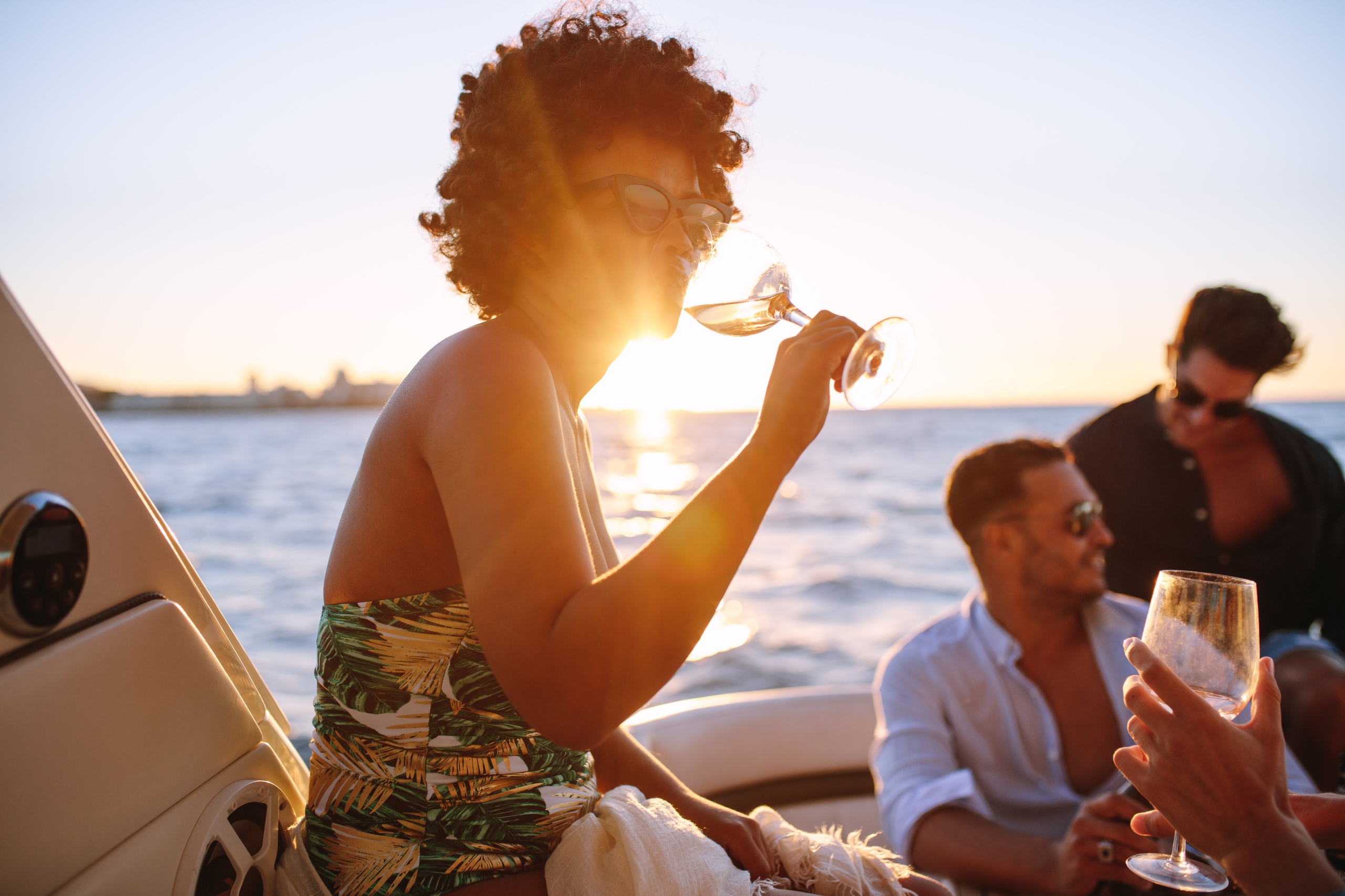 People on a boat enjoying drinks at sunset.