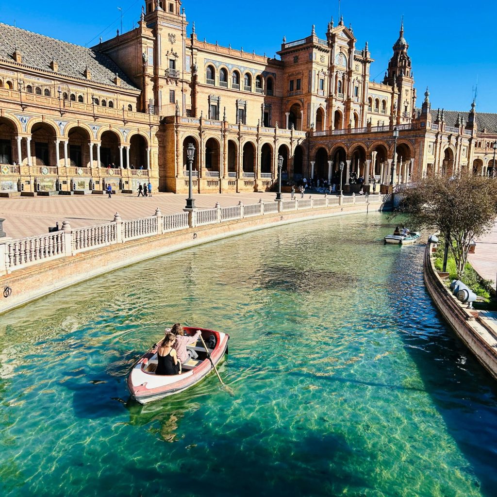 Couple rowing boat on canal at Plaza de España, Seville, sunny day.