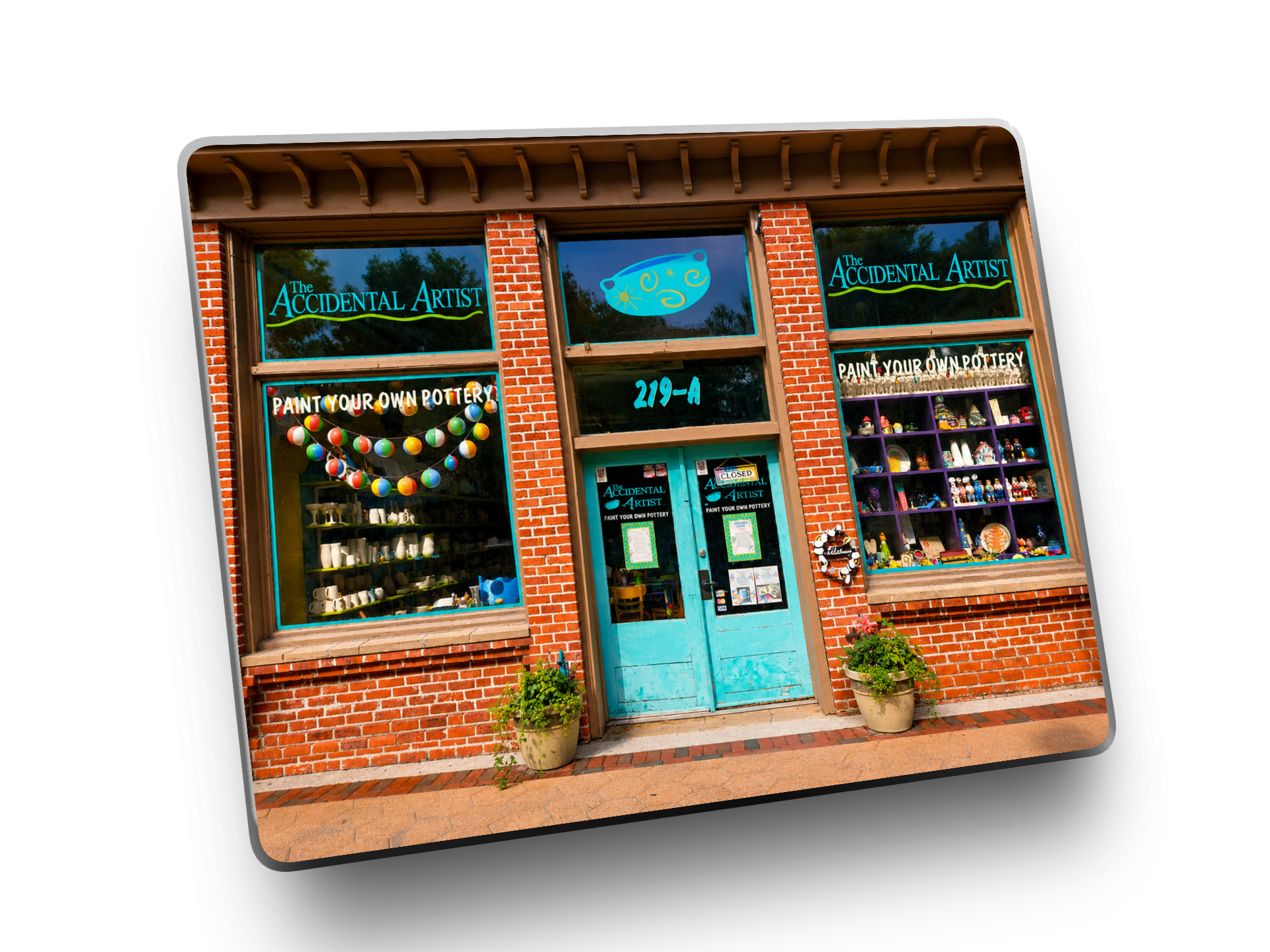 Brick storefront of 'The Accidental Artist' with colorful pottery displays.