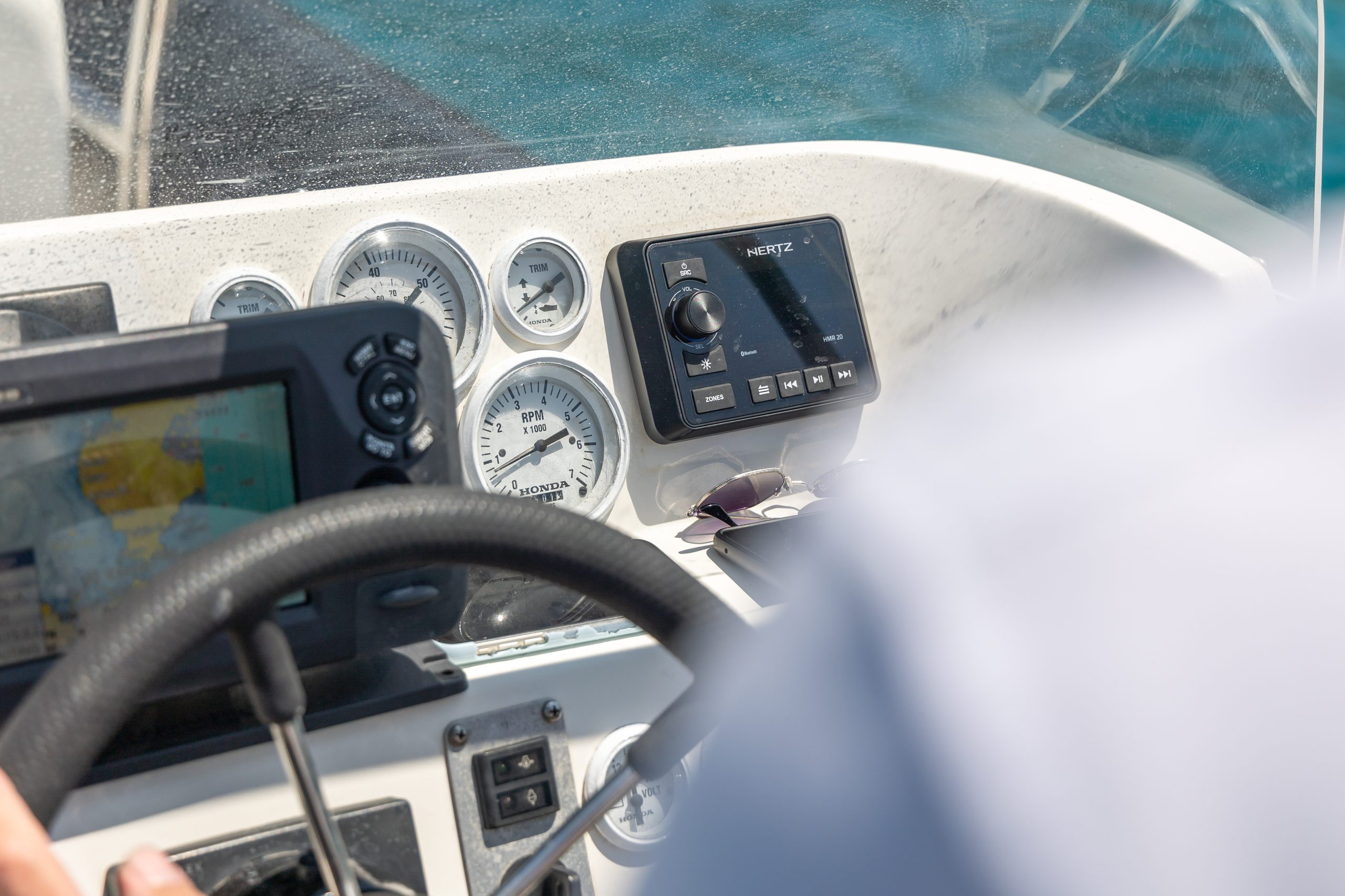 Close-up of a boat's steering console with gauges and navigation device.