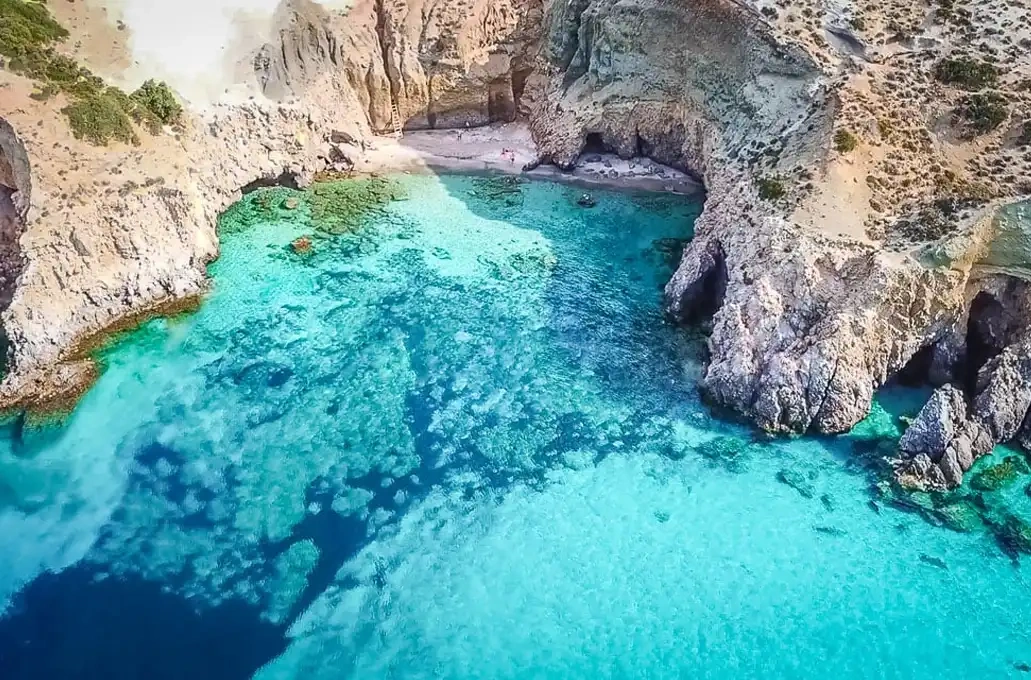 Aerial view of a cove with turquoise water and rocky cliffs.