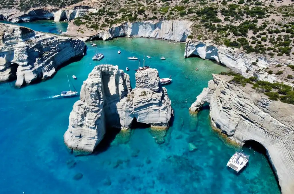 Aerial view of boats near rocky cliffs and turquoise water.